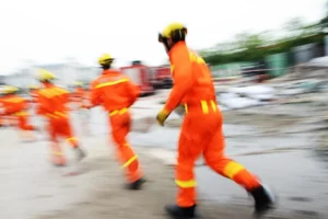 A group of people in orange uniforms are running down a street.